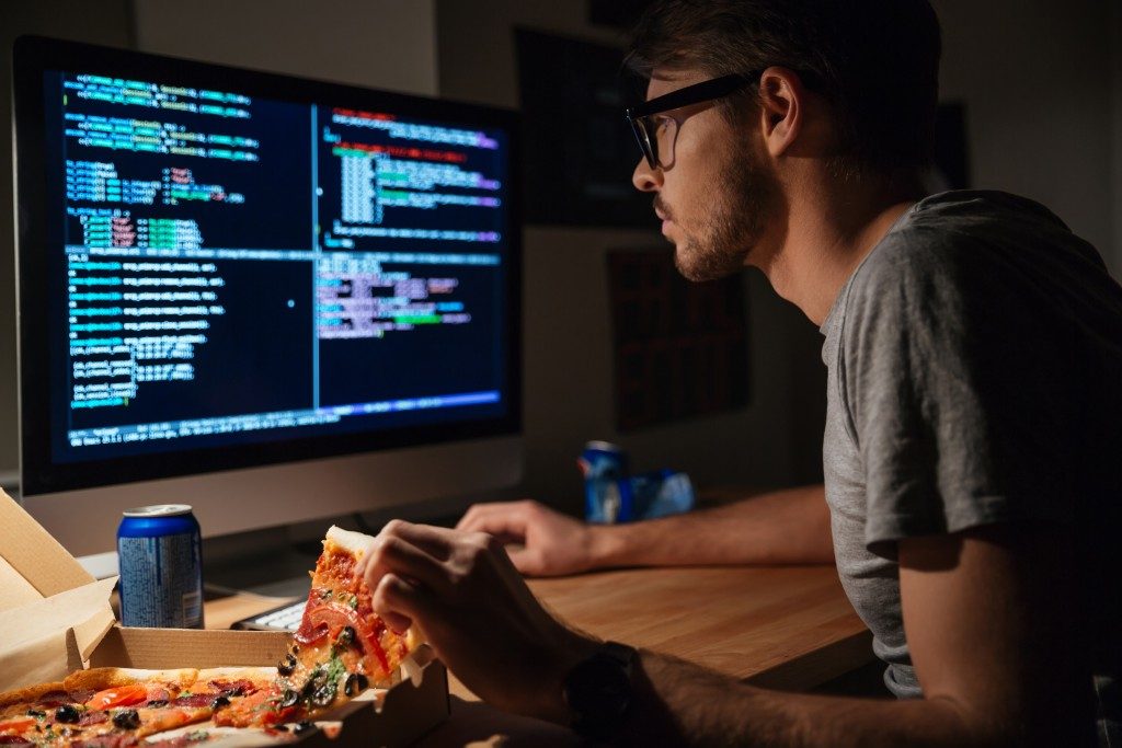 programmer doing coding whilst eating pizza