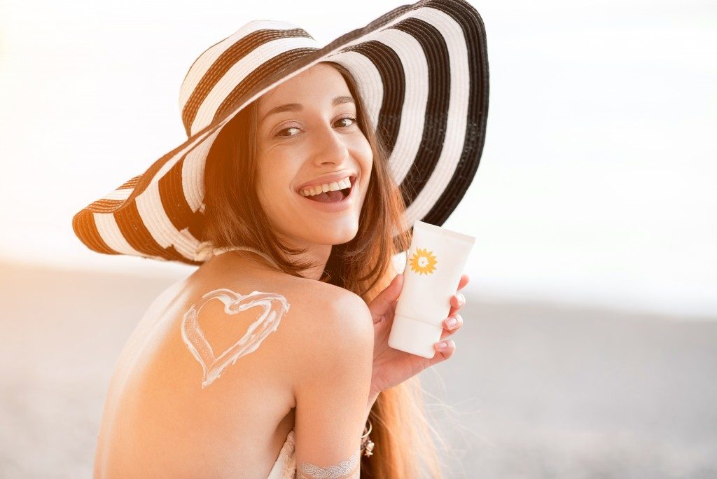 Woman smiling and holding sunscreen