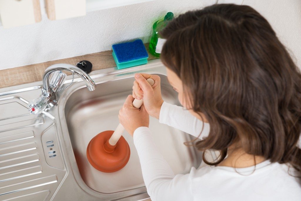 Unclogging the drain using a plunger