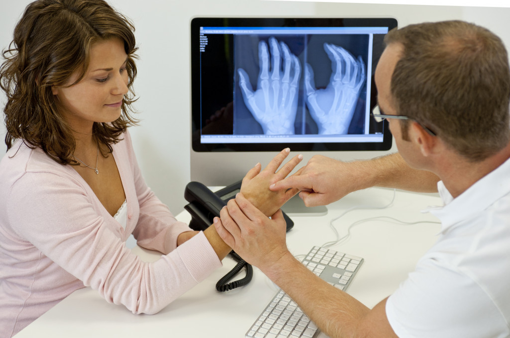 a doctor checking the patient's hands while looking at an x-ray