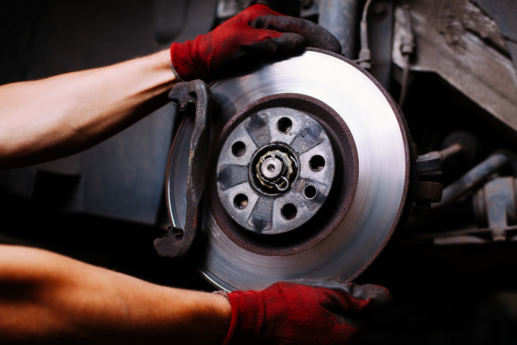 Close up portrait of hands fixing disc brake of car