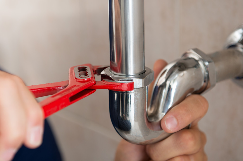 A plumbing fixing a pipe with a wrench