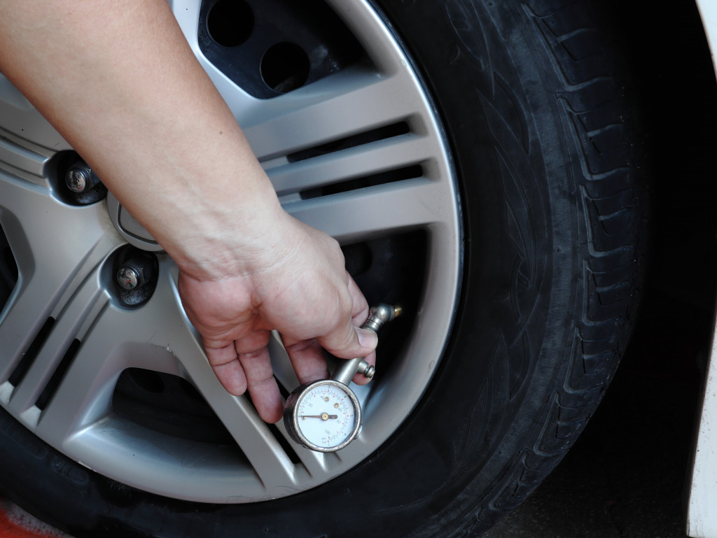 View of a man's hand checking car air pressure with a small meter 