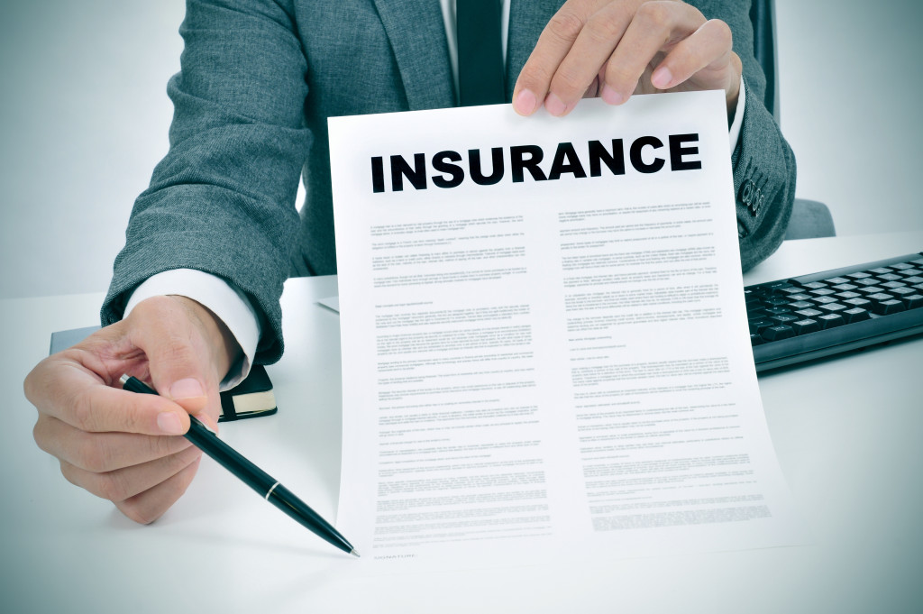 A businessman holding a pen and insurance policy document