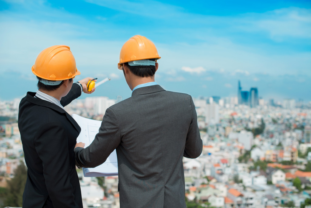 Businessmen in hard hats looking at blueprints in front of a cityscape