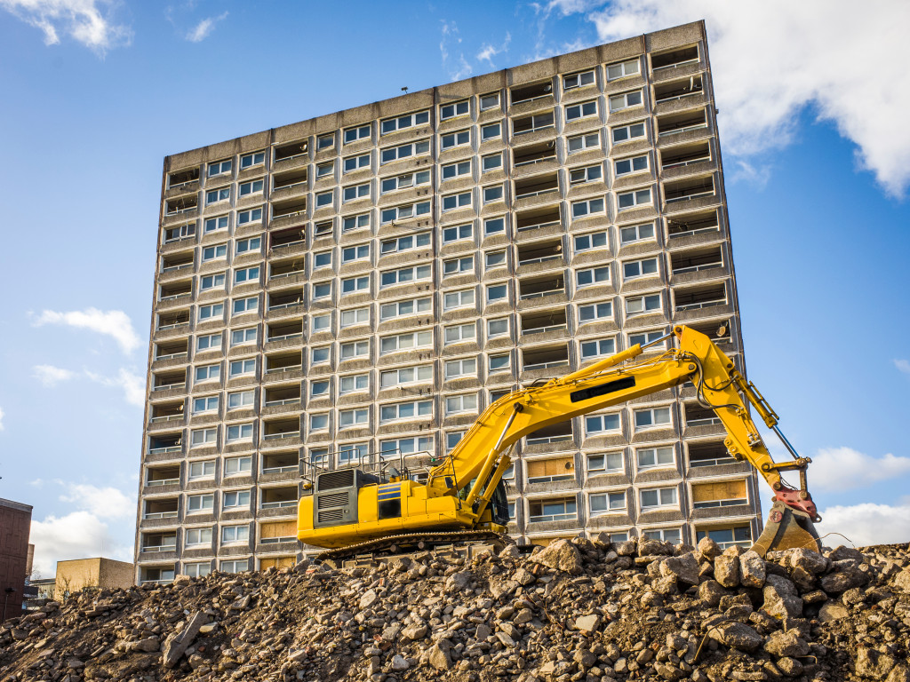 A yellow excavator in front of a building under construction