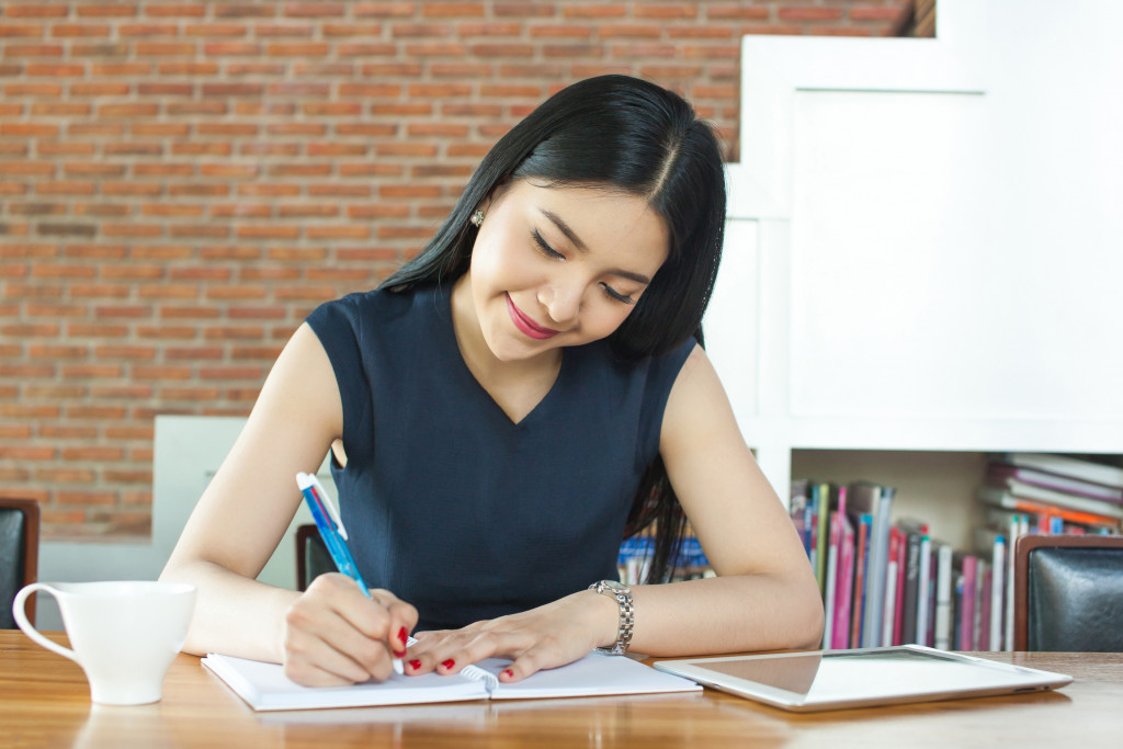 A young woman writing in a journal at home