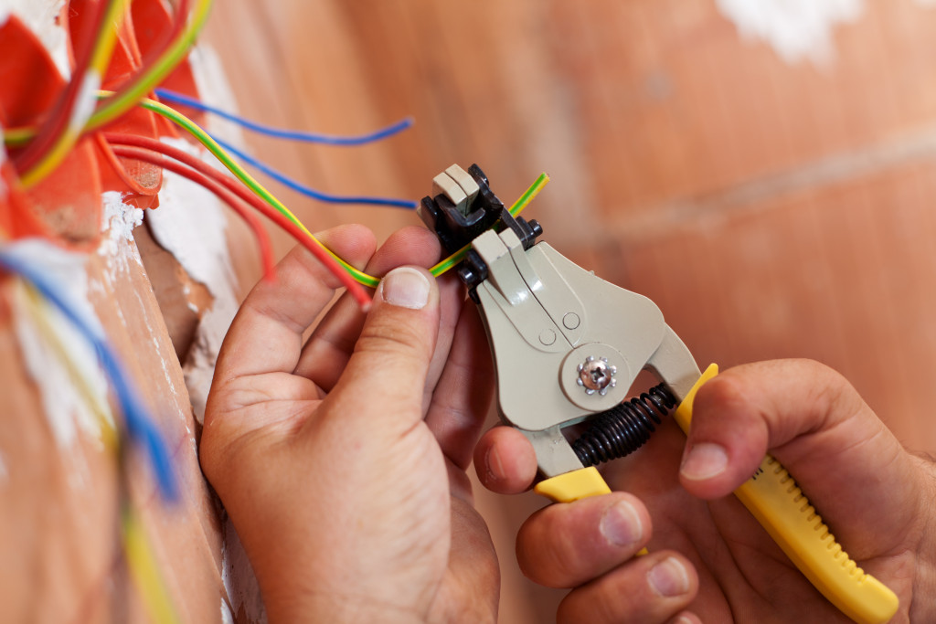 An electrician removing wire insulation with pliers