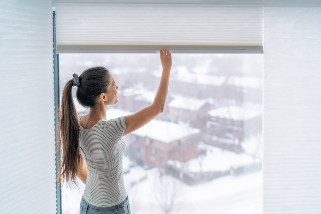 A woman lifting the window shades