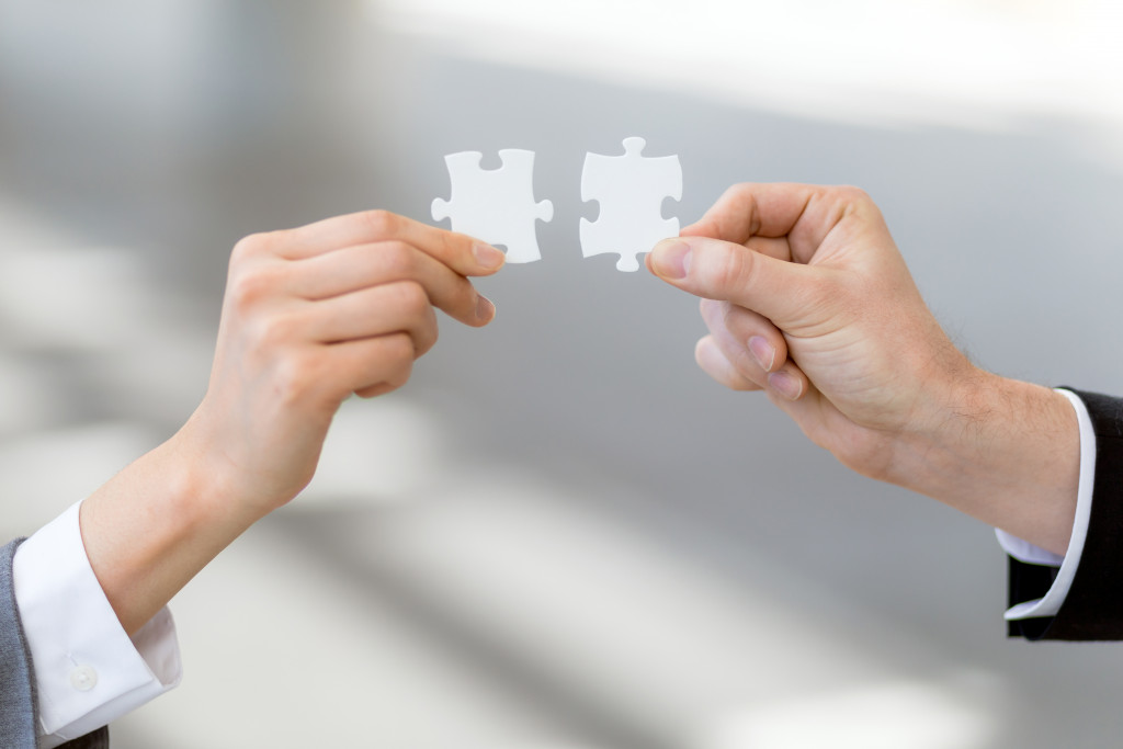 two business people hand fitting a puzzle piece together