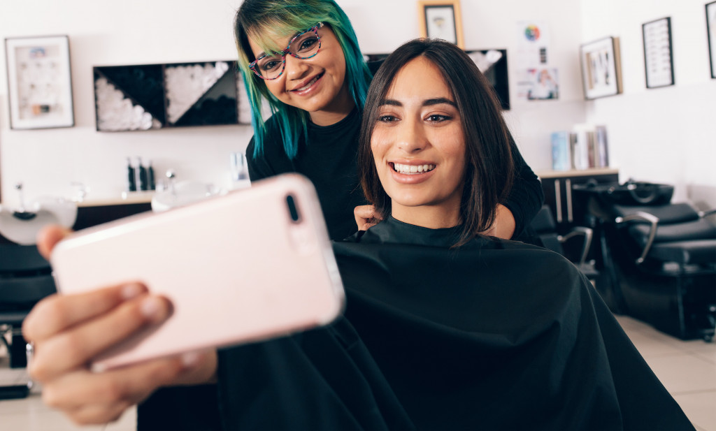 woman taking selfie at salon with hairstylist