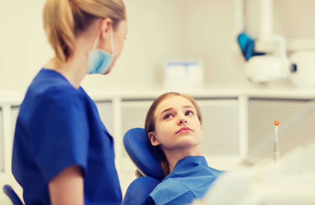 A dentist talking to a young patient while in the clinic