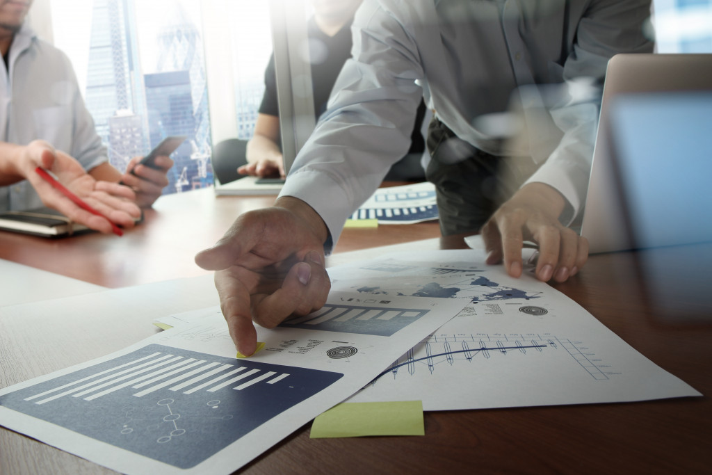 businessman pointing at graphs with other business people in the meeting