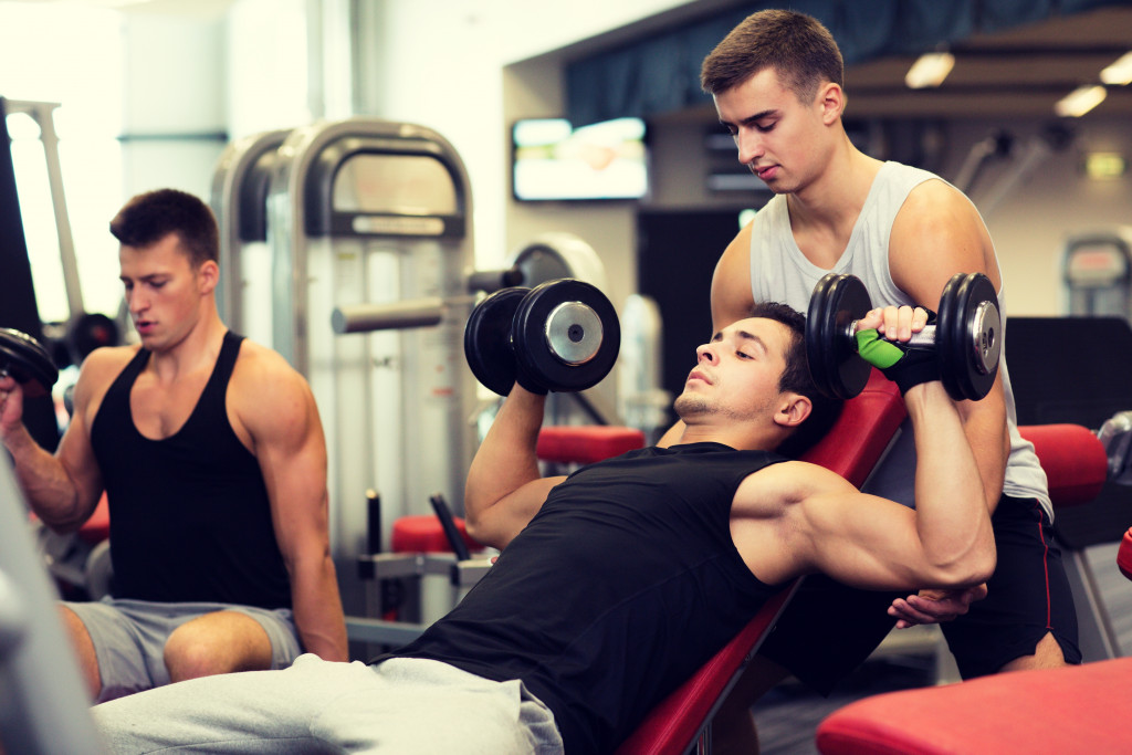 Three handsome and muscular men working out in the gym