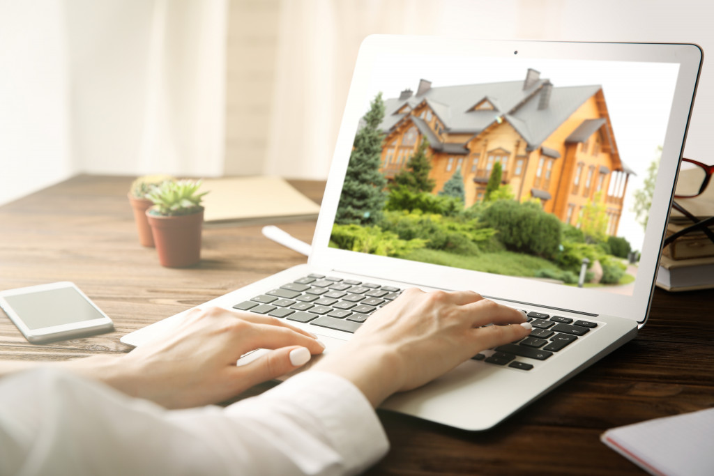 woman using laptop with house on screen to choose home to buy