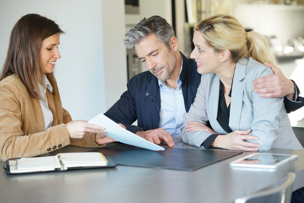 couple talking to female real estate agent in the house table 