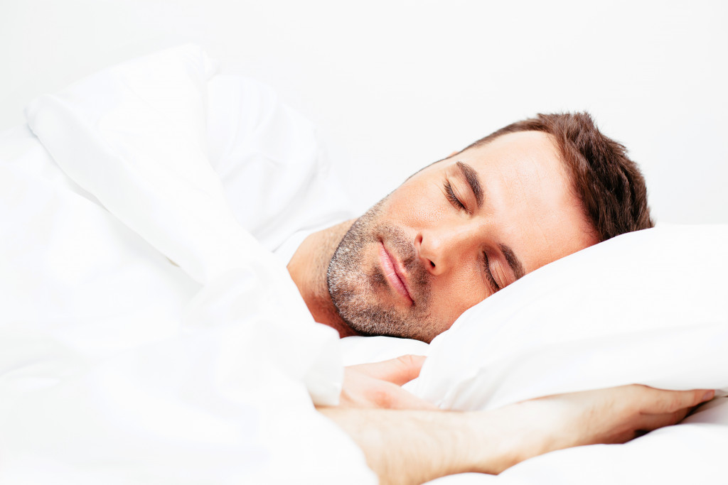 A man sleeping on a white bed