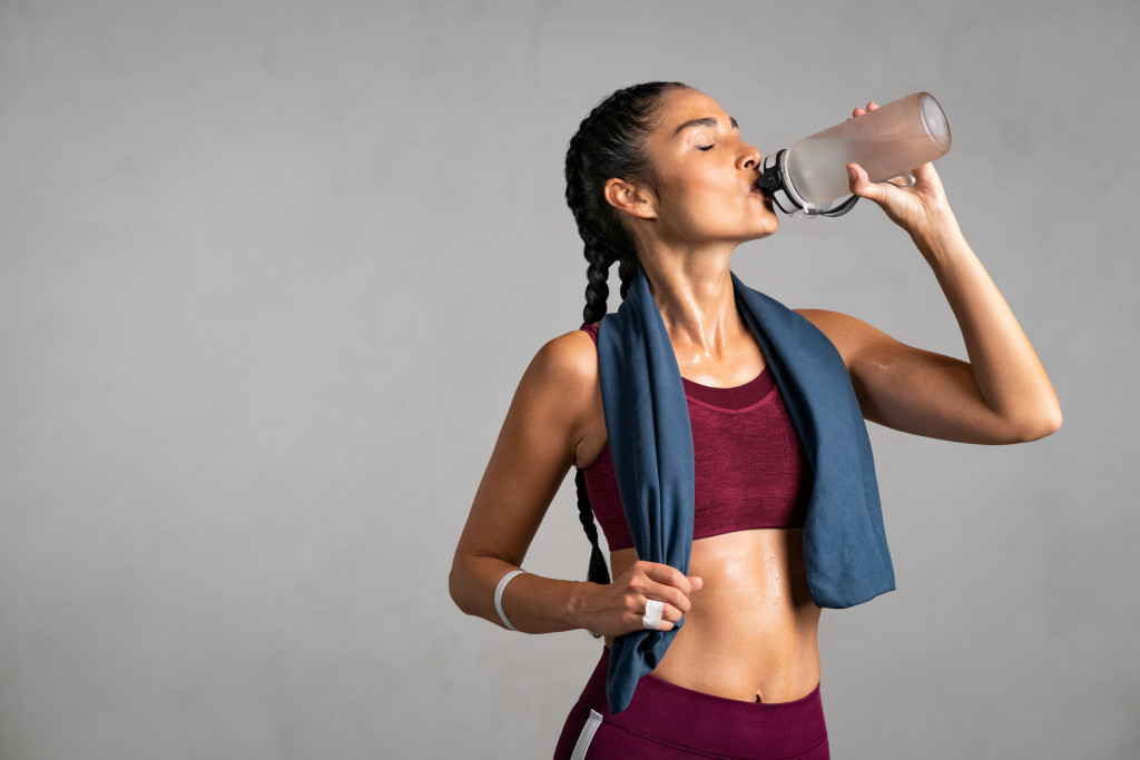 Young woman drinking water after exercising.