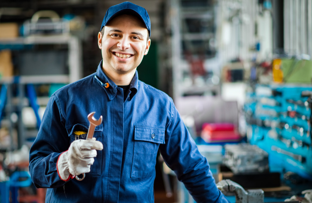 An auto mechanic smiling to the camera in his garage