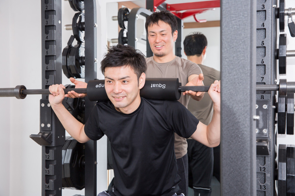 fitness coach helping a man on weights