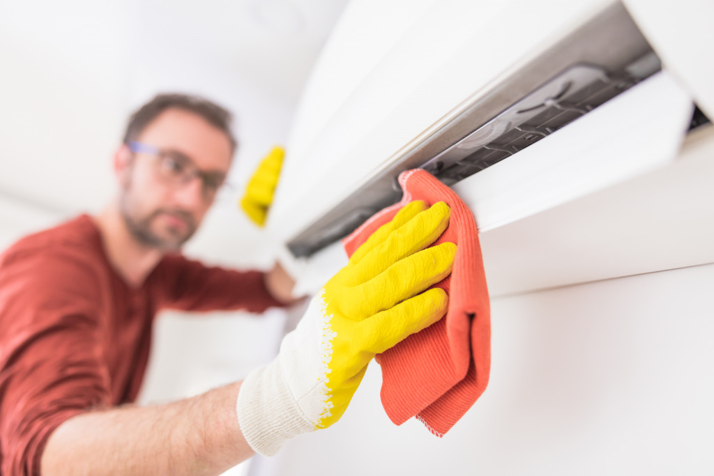 man with glasses cleaning an air conditioning unit