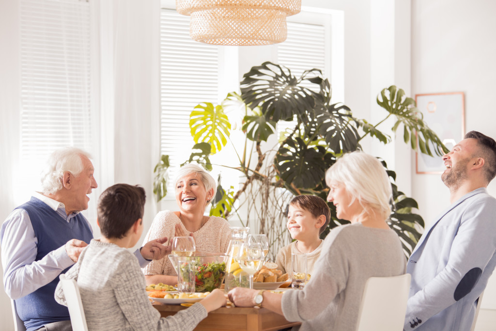 happy family with elderly parents and children and grandchildren eating in table