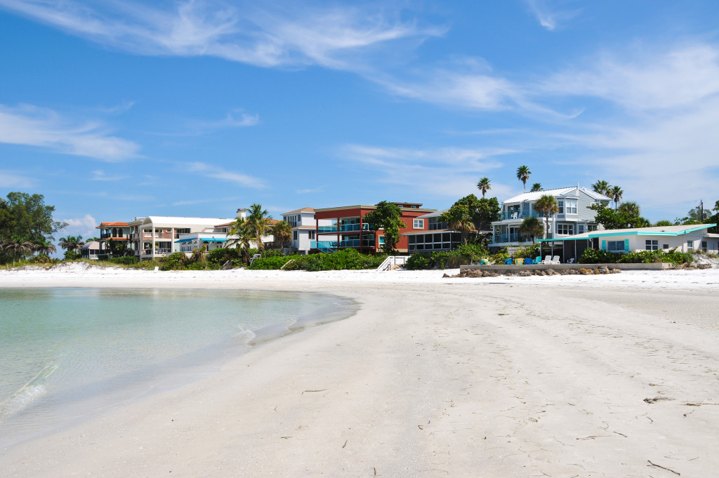 blue sea in a white sand beach with resorts and buildings at the distance