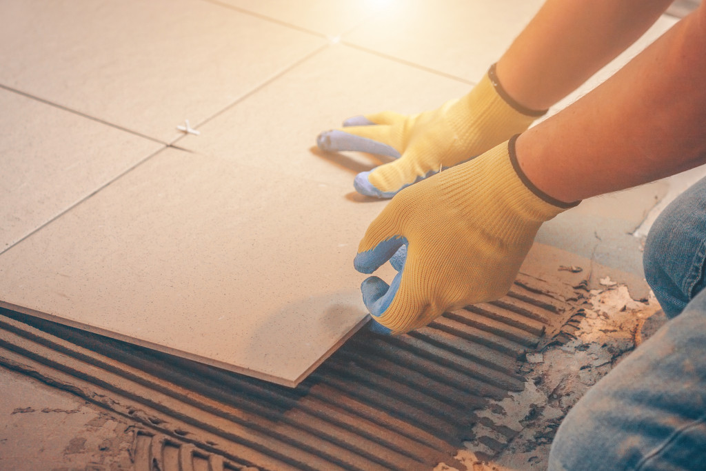 A worker installing tiles as flooring