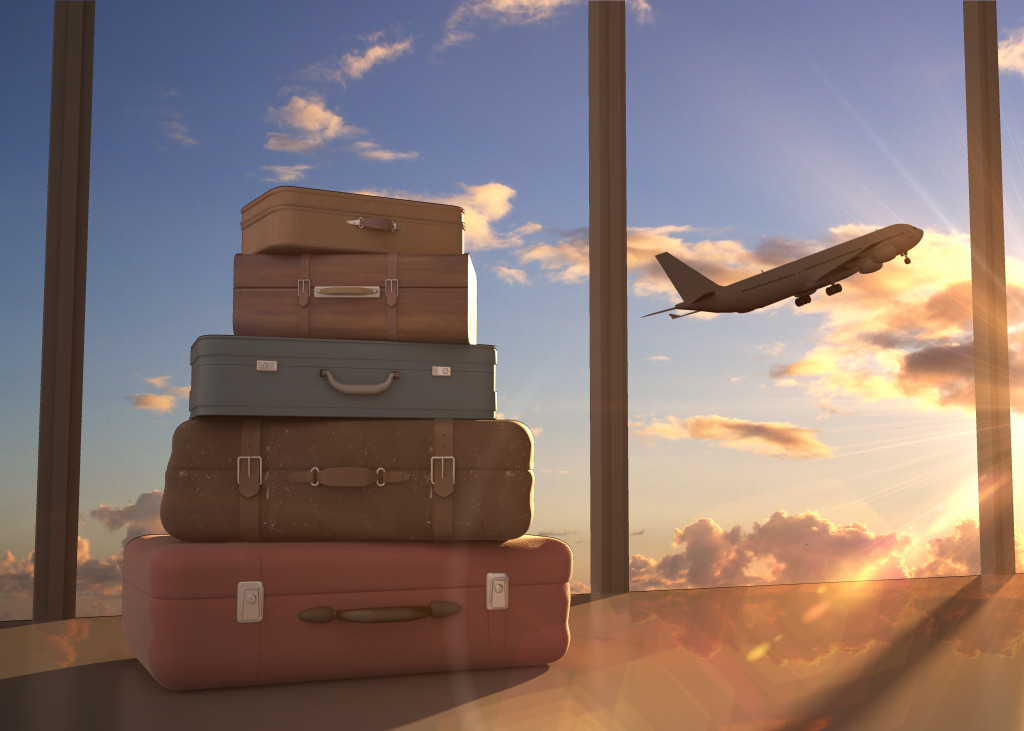 stacks of luggages with the airplane flying in the sky as background