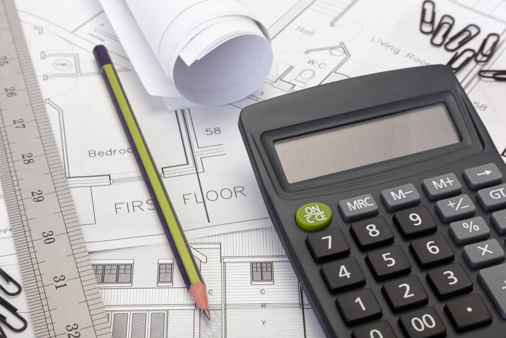 calculator, pencil, and ruler on top of house floor plans