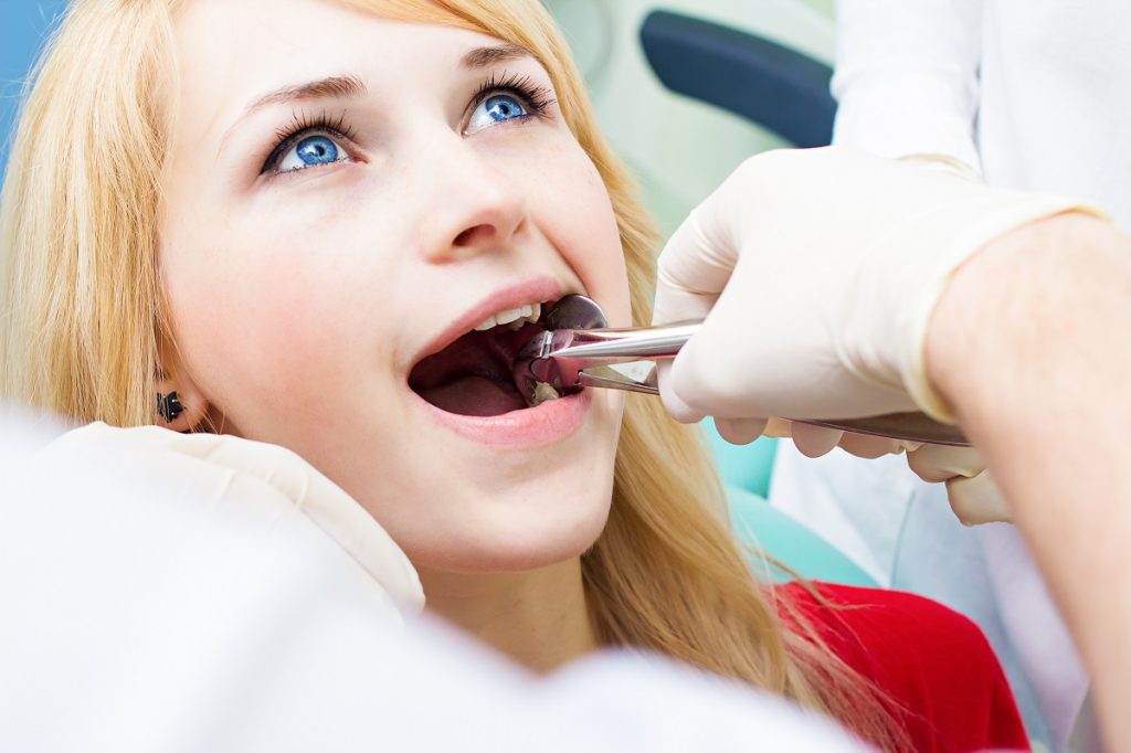 a dentist performing extraction procedure at woman