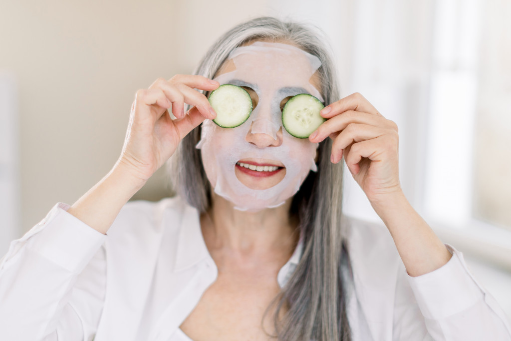 social elderly woman with cucumbers and face mask in her face