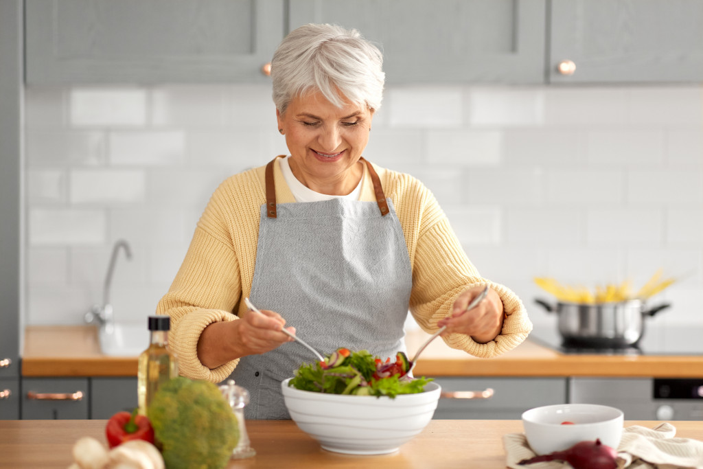 elderly woman making a salad bowl in her kitchen