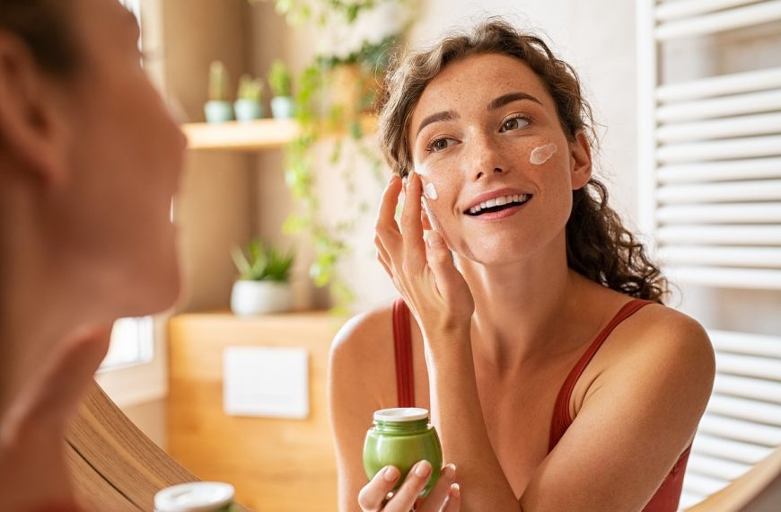 woman applying skincare in front of mirror